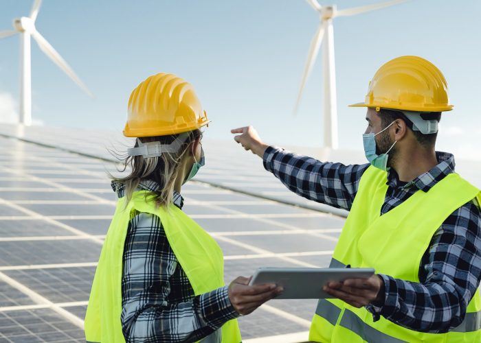 people-working-for-alternative-energy-with-wind-turbine-and-solar-panel-while-wearing-face-mask.jpg